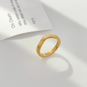 Gros plan sur une bague ondulée dorée avec texture double crête sur fond artistique