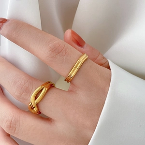 Détail de deux bagues minimalistes dorées sur un tissu en soie blanche brillante