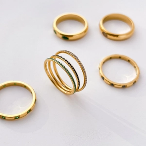 Macro detail of gold-plated titanium steel rings with green and white crystal accents