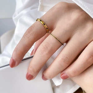 Detail of gold titanium rings with green zircons and black spinel on model finger