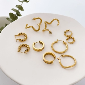 Collection of minimalist gold-plated geometric hoop earrings with zircon on a white plate