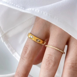 Detail of a gold plated eye-shaped marquise ring stacked with a micro-pavé crystal band
