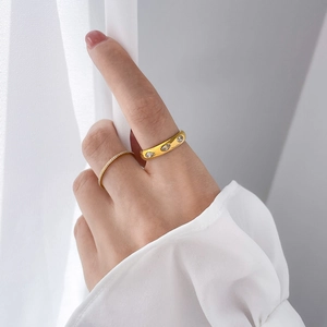 Close-up of stacked gold titanium rings with crystal pavé and emerald-cut stones