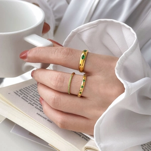 Three-piece gold plated ring set with green zircon stones on elegant lifestyle background