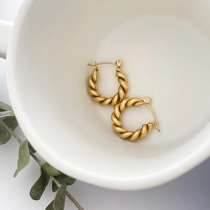 Macro detail of gold twisted hoop earrings showing refined metal texture and craft