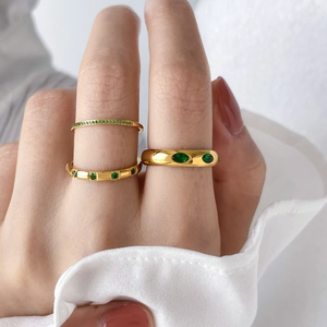 Close-up of gold titanium rings set with green zircon stones on a model's hand