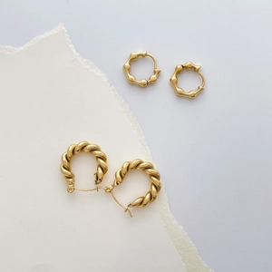 Close-up of golden geometric twisted rope and textured bamboo-style hoop earrings