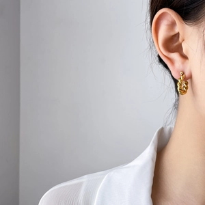 Close-up of golden twist rope texture titanium steel earrings on female model