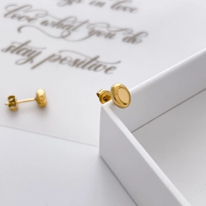 Detail of minimalist gold-plated oval bean earrings on a jewelry display box