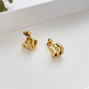 Detail view of triple-layered golden C-shaped hoop earrings with a polished metallic finish