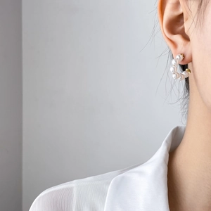 Elegant C-shaped pearl earrings with gold-toned metal plating shown on model