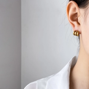 Close-up of three interlocking gold hoop earrings worn by a model in a minimalist style