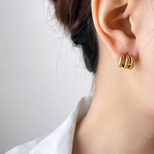 Close-up of triple-layered gold hoop earrings worn by a model in a minimalist style