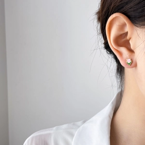 Close-up of pink tulip enamel stud earrings with gold trim worn by a model
