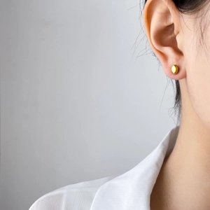 Close-up of minimalist oval gold stud earrings on a female model for a chic look