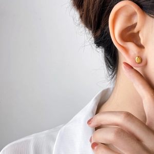 Polished gold oval stud earrings on model for a minimalist aesthetic look