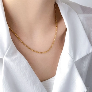 Close-up of minimalist 18k gold plated titanium chain with oval and round beads on neck