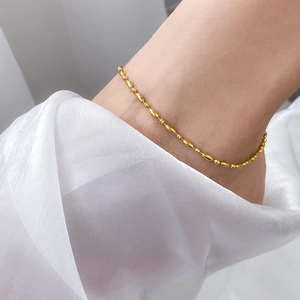 Detail of 18k gold plated titanium anklet with small round and oval beads on satin