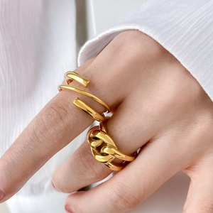 Close-up of gold geometric twist and chunky chain link rings on model with knit sleeve