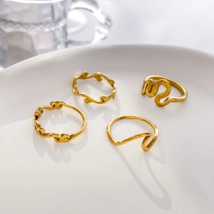 Minimalist gold ring set with abstract seagull and wavy leaf designs on ceramic tray
