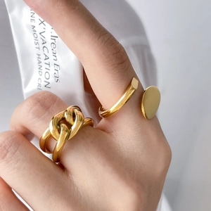 Close-up of gold plated chain link and oval signet rings set on a model's hand