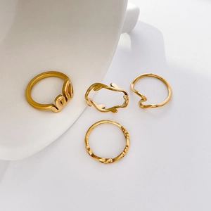 Detailed view of four minimalist gold stacking rings featuring leaf and wave designs