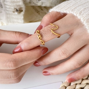 Close-up of golden wavy rings on hand with minimalist aesthetic and cozy knitwear background