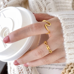 Minimalist gold seagull and wave rings set on model holding a coffee cup