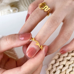 Close-up of golden wavy line ring and delicate leaf branch ring worn on fingers