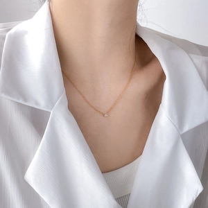 Minimalist gold chain necklace with a tiny rectangular zircon pendant on a woman