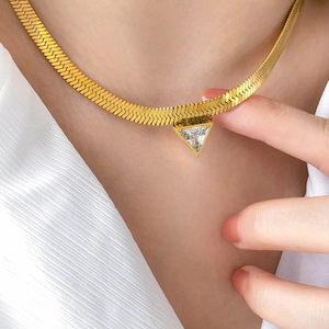 Close-up of gold snake chain necklace featuring a geometric triangle zircon pendant