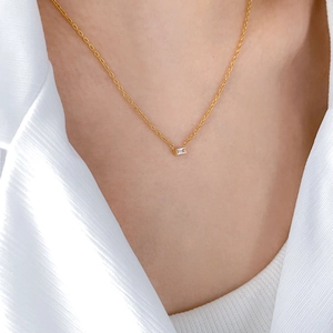 Close-up of minimalist gold thin chain necklace with a rectangular zircon pendant on model