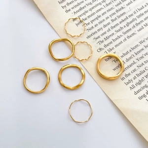 Stackable gold wavy and smooth minimalist rings set on vintage book pages