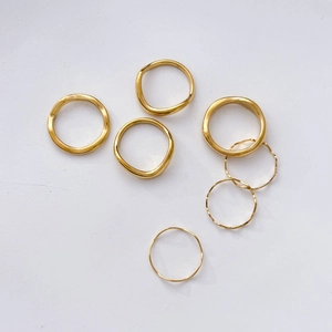 Close-up of a stackable golden wave-textured ring set with polished irregular surfaces