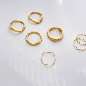 Flat lay of minimalist irregular wavy gold rings with elegant water ripple shadows