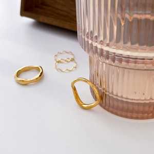 Close-up of minimalist stacked gold wavy rings with irregular polished texture on white