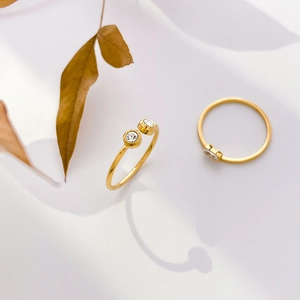Detail of elegant gold twist rings with fresh pearls and zircons on a minimal background