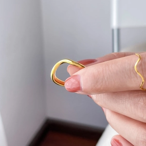 Close-up of a wavy gold stackable ring with a polished minimalist irregular design