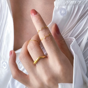 Stackable gold wavy ring set with minimalist irregular curved design on model's hand