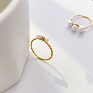 Detailed view of dainty gold twist rings featuring freshwater pearls and zircon accents