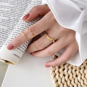Detail of stacked gold wavy rings on model's fingers with elegant minimalist style