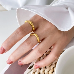 Detail of stackable gold wave rings with irregular twisted design on a woven mat