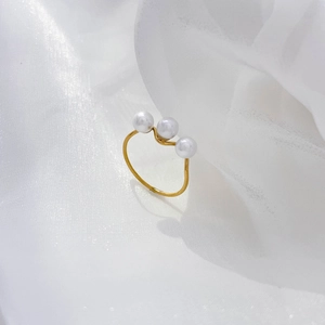 Detail of three white freshwater pearls on a slim golden twist band over white silk fabric