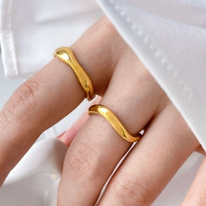Macro shot of two stacked minimalist wave rings in polished gold on model's fingers