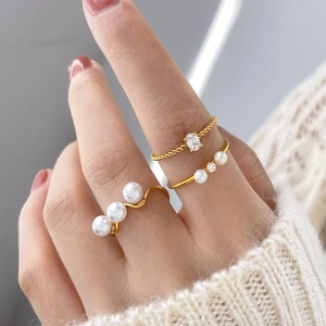 Detail of three-piece gold ring set featuring freshwater pearl and zirconia accents