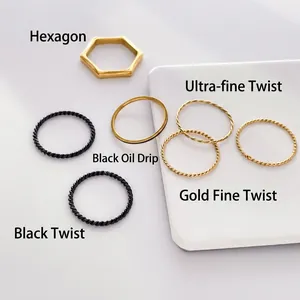 Detail of minimalist gold hexagonal, thin twist, and black drip oil stacking rings set