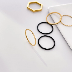 Detail view of minimalist gold and black stacking rings with thin twist and hexagon design