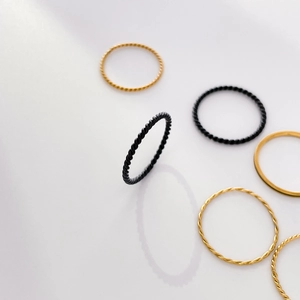Detail of stacked gold and black minimalist hexagon rings with twisted rope textures