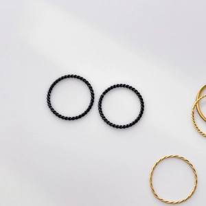 Detailed macro view of minimalist gold and black twist rope rings in a stacked arrangement
