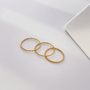 Close-up of three delicate gold-plated twisted rope rings with fine spiral texture details